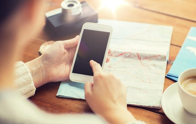 A close-up shot of hands using a smartphone app to track travel expenses, with a blurred map of the US in the background.