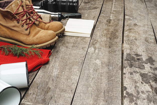 A detailed flat lay of essential, budget-friendly hiking gear: a well-worn backpack, sturdy hiking boots, a refillable water bottle, trail mix, and a map, all on a weathered wooden surface.