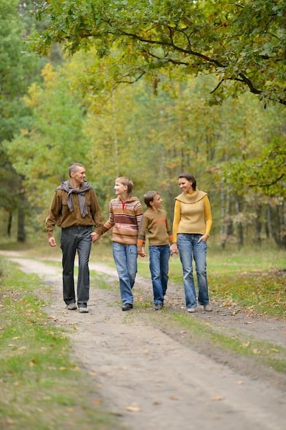 A family (parents and two children around ages 8-12) hiking together on a clearly marked trail in a national park, smiling and enjoying the scenic view. They are wearing comfortable hiking gear.