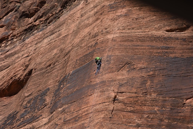 A mountain biker expertly navigating a technical singletrack trail in Moab, Utah, surrounded by distinctive red rock formations with a clear blue sky overhead.