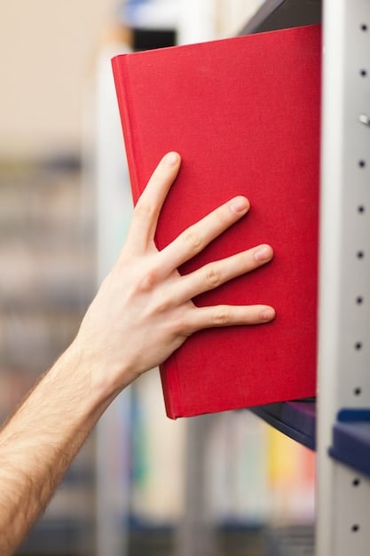 A close-up shot of a student's hand holding a credit card, tapping it on a point-of-sale terminal at a university bookstore, with a blurred background of shelves filled with books and study supplies.