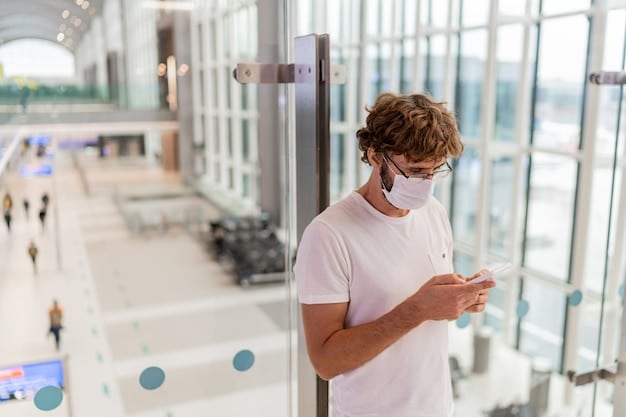 A traveler looking directly into a biometric facial recognition scanner at an airport security checkpoint, with bright, clean surroundings indicating a modern facility.