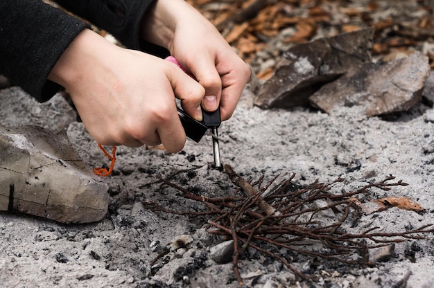 A skilled individual demonstrating the technique of starting a fire using a ferrocerium rod, with a small flame beginning to ignite dry tinder.