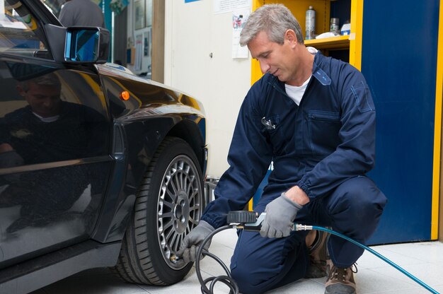A mechanic performing a pre-trip inspection on a car, checking tire pressure and fluid levels. Various car maintenance tools are visible, emphasizing the importance of vehicle preparation for The Ultimate Guide to Planning a Cross-Country Road Trip in the US: 2025 Edition.