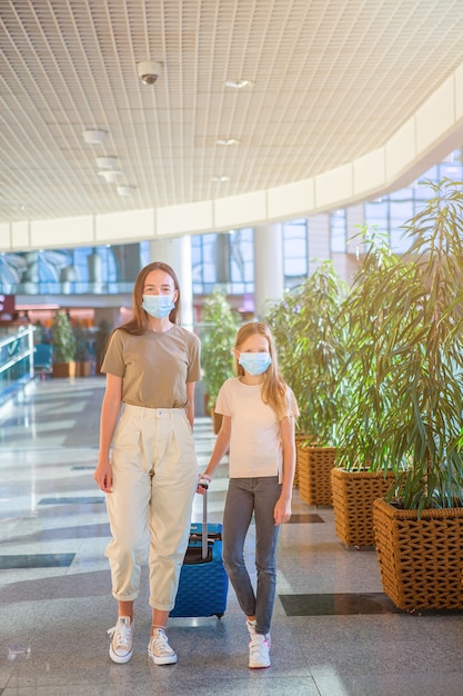 An image of a family wearing masks and practicing social distancing in a crowded airport terminal. The image relates to the section 
