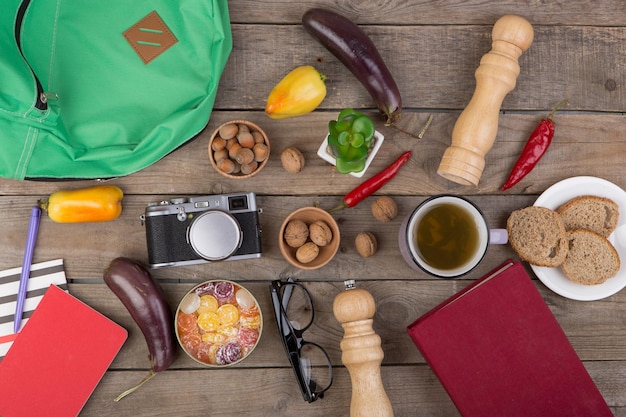 A close-up of various camping gear items laid out on a picnic table, including a tent, sleeping bag, cooking stove, first aid kit, and a map.