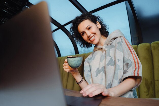 A person is shown smiling while booking flights on a laptop at a cozy café, illustrating the ease and satisfaction of using travel rewards. This signifies how to Maximize Your Points: The Best Time to Book Travel with Rewards in 2025, leading to enjoyable travel experiences.