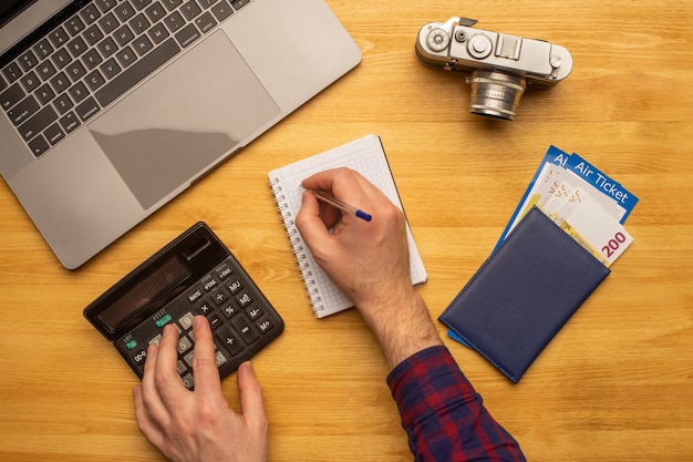 A close-up of a hand calculating travel expenses on a calculator, with airline tickets and a map in the background, symbolizing careful financial planning in light of Airline Baggage Fee Updates: How the New 12% Average Increase Impacts Your Travel Budget.
