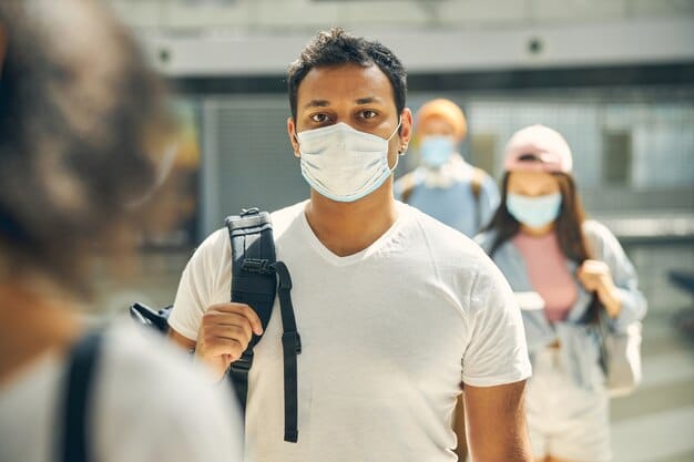 A close-up shot of a healthcare worker administering a COVID-19 test to a cruise passenger before boarding. The passenger is wearing a mask, and the background shows a modern cruise terminal with signs indicating health and safety protocols. The image is well-lit and conveys a sense of professionalism and reassurance regarding Cruise Line Health and Safety Protocols: What's Changed and What You Need to Know Before Boarding.
