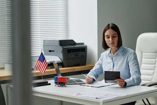 A person sitting at a desk, carefully filling out a US visa application form. The scene is focused and organized, conveying the importance of accuracy and attention to detail in the application process. The image emphasizes the need to understand The Latest on US Visa Requirements: Updates for International Travelers Visiting in 2025.