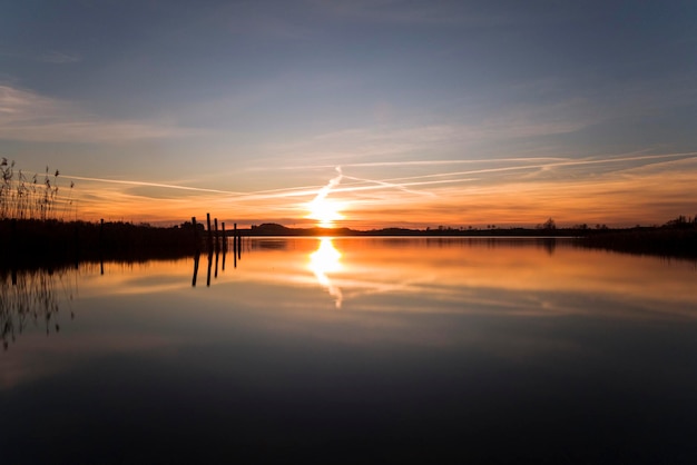 A serene landscape photo taken at golden hour, showcasing the rule of thirds. The horizon is placed along the lower third of the frame, with the sky filling the upper two-thirds. Leading lines draw the viewer's eye towards a distant mountain. Emphasize the composition techniques learned in the course.