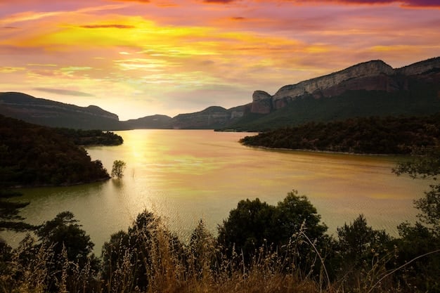 A calm lake reflecting a vibrant sunset, surrounded by mountains, possibly in the Rocky Mountains or Grand Teton National Park, captured during the golden hour.